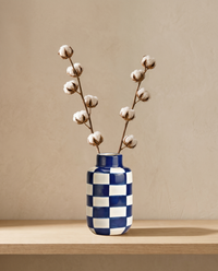 Vase Indigo blau-weiss mit Baumwolle, Look auf Holzbrett vor warmer Wand