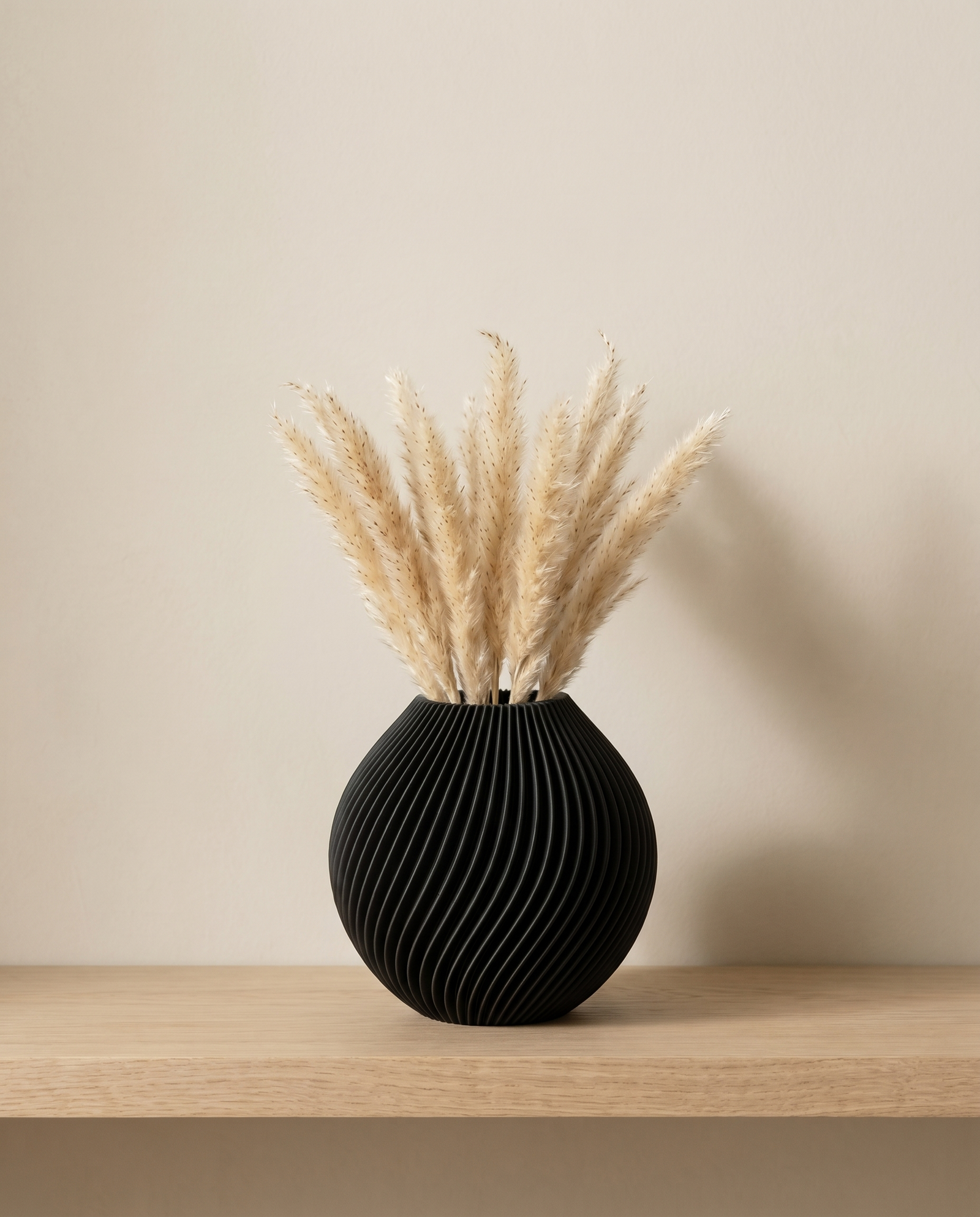 Spira Vase in Schwarz mit Pampasgras, Look auf Holzbrett vor warmer Wand